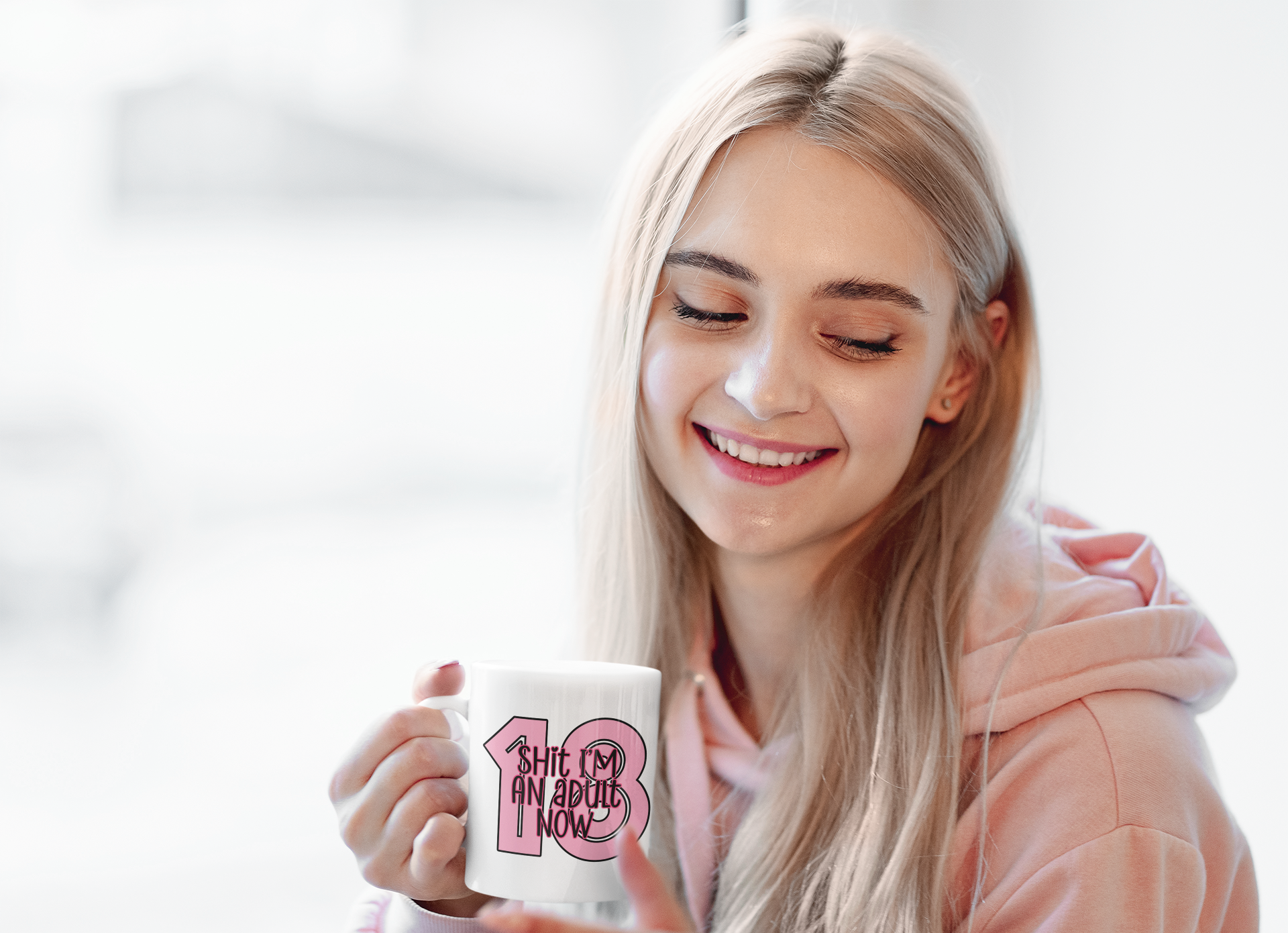 White mug with a bold 18 in baby pink and over the top it reads shit i'm an adult now